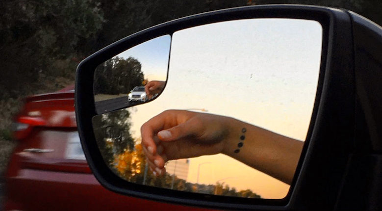 Author's hand resting out the window, reflected in the side mirror.